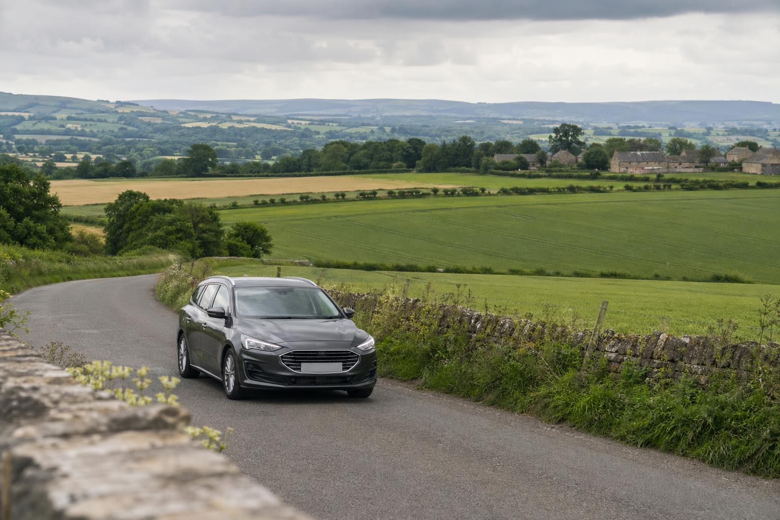 Estate hire car travelling on a rural road near Crewkerne with open farmland in the background.